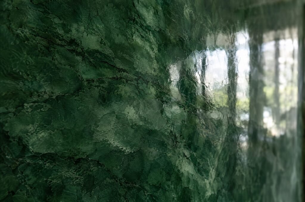 Close-up of high-gloss deep green polished Venetian plaster (stucco veneziano) with marble-like depth and reflections