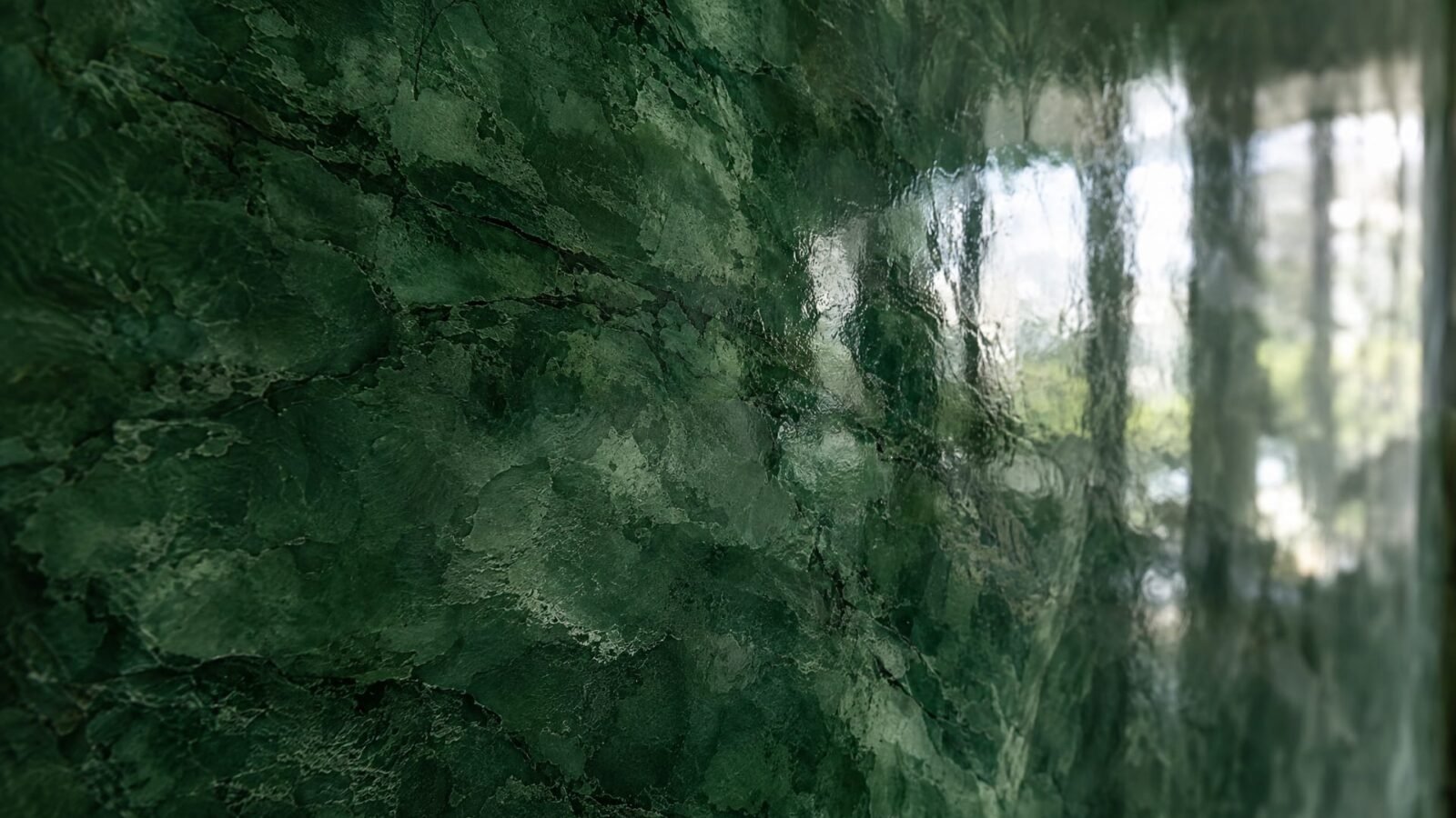 Close-up of high-gloss deep green polished Venetian plaster (stucco veneziano) with marble-like depth and reflections