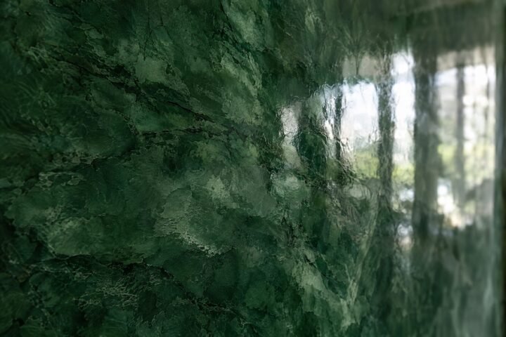 Close-up of high-gloss deep green polished Venetian plaster (stucco veneziano) with marble-like depth and reflections