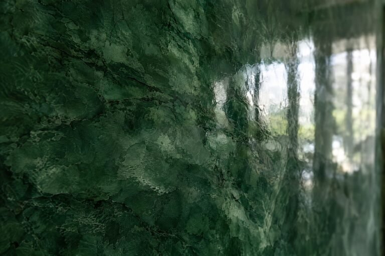 Close-up of high-gloss deep green polished Venetian plaster (stucco veneziano) with marble-like depth and reflections